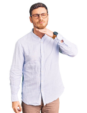 Handsome young man with bear wearing elegant business shirt and glasses cutting throat with hand as knife, threaten aggression with furious violence