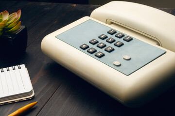 Vintage analog phone on a desktop along with a notepad and a plastic pencil