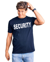 Young handsome man wearing security t shirt confuse and wondering about question. uncertain with doubt, thinking with hand on head. pensive concept.