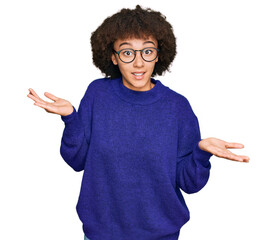 Young hispanic girl wearing casual winter sweater and glasses clueless and confused expression with...