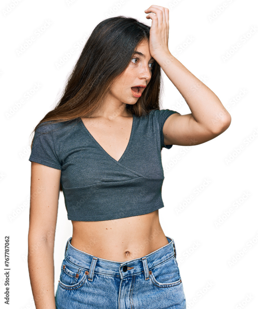 Sticker Young beautiful teen girl wearing casual crop top t shirt surprised with hand on head for mistake, remember error. forgot, bad memory concept.