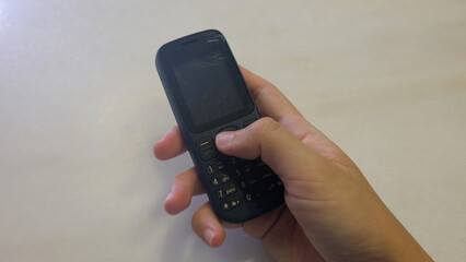 Hand holding an old fashioned cellular phone, with a blank screen. 