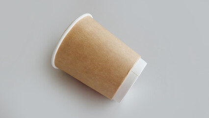 A clean and new brown disposable cup, laying on a gray surface.