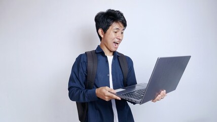 Surprised handsome young Asian man holding a laptop