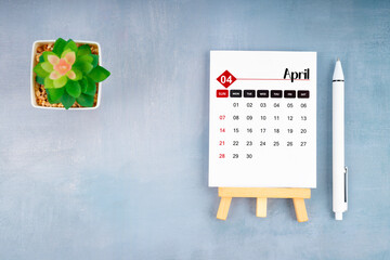 2024 April calendar page and pen with plant pot on blue background. - obrazy, fototapety, plakaty