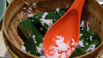 An empty serving basket with banana leaf and some leftover cooked white rice, with an orange rice ladle.