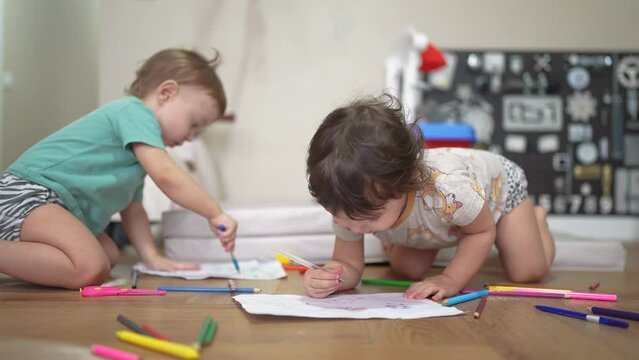 children sit on the floor and draw on paper. happy family child dream concept. baby boy and girl sitting indoors on the floor and drawing with pencils on paper. children lifestyle draw a