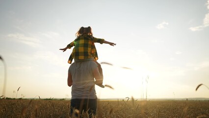 father and daughter in the park. happy family a behind his back walking in a wheat field silhouette. happy family kid dream concept. father and daughter piggyback happy sunset family - 767792242