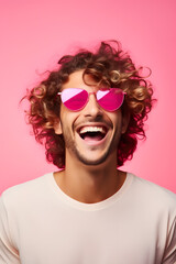 Young man with curly hair wearing pink sunglasses on pink background	