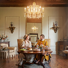 Noble, couple and luxury with food, feast and renaissance home or house and dining table. King,...