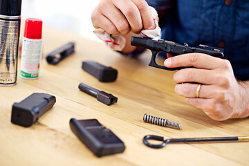 Hands, man with gun cleaning process at table for safety, self defense and handgun assembly....