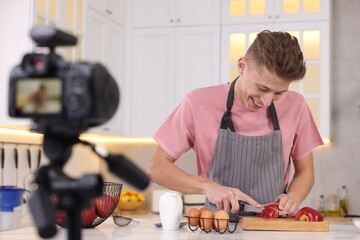 Smiling food blogger cooking while recording video in kitchen