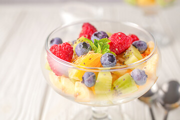 Fresh fruit salad on a light wooden table background