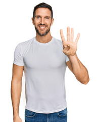 Handsome man with beard wearing casual white t shirt showing and pointing up with fingers number four while smiling confident and happy.