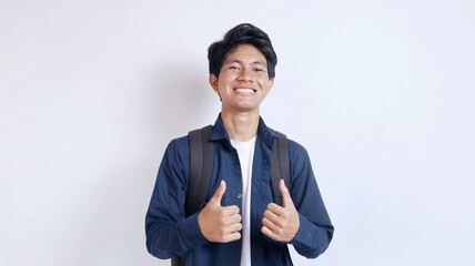 Portrait of young handsome Asian student excited gesturing showing thumbs up on isolated white...