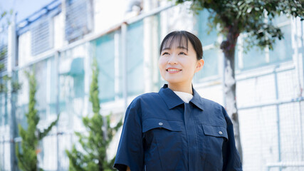 工場のような背景で製造業などの作業着を着た女性のイメージ