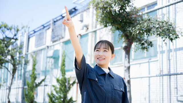 Image of a woman in manufacturing or other work clothes against a factory-like background
