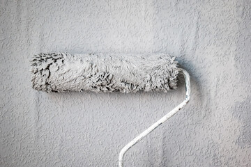 Paint roller extendable pole over painted woodchip wallpaper wall during home renovation in england...