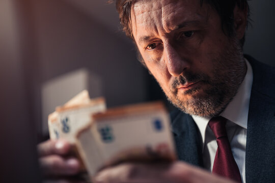 Closeup of businessman counting euro banknotes cash money in office late at night
