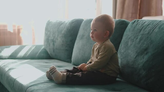Small kid toddler watching tv. happy family child sitting on sofa alone. baby watching television. kindergarten learning lifestyle development concept. Curious Little baby boy