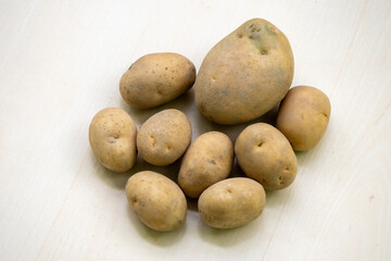 Fresh raw potatoes (Solanum tuberosum) on a wooden background. In the Bengali language, it is...