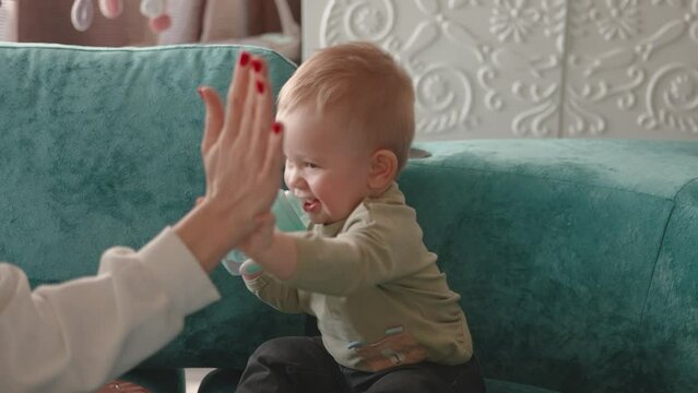 Children doing high five with one year old baby. cheering with infant toddler. Family mother play together close-up hands parent and baby child. Hand game. Сlose-up moment of family interaction 