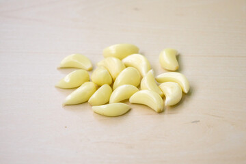 Fresh raw garlic cloves isolated on a wooden background. Its scientific name is Allium sativum....