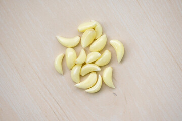 Raw garlic cloves isolated on a wooden background. Its scientific name is Allium sativum. Locally in Bangladesh, it is called Rosun. Top view