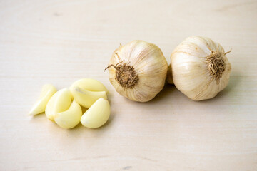 Fresh garlic cloves and two whole garlic on a wooden background