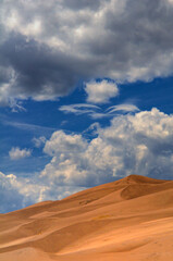 Fototapeta na wymiar An artistic image capturing the contrast of dark, billowing clouds and the smooth, golden dunes beneath them, portraying a sense of tranquility