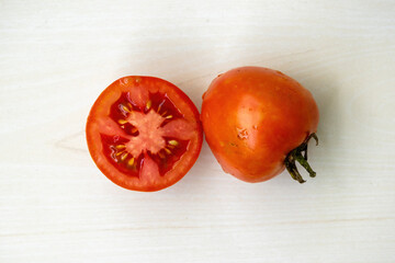 Fresh ripe red tomatoes whole and half isolated on a wooden background. Tomatoes can be a valuable...