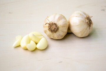 Raw garlic cloves and whole garlic on a wooden background