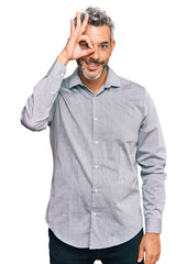 Fototapeta premium Middle age grey-haired man wearing casual clothes doing ok gesture with hand smiling, eye looking through fingers with happy face.