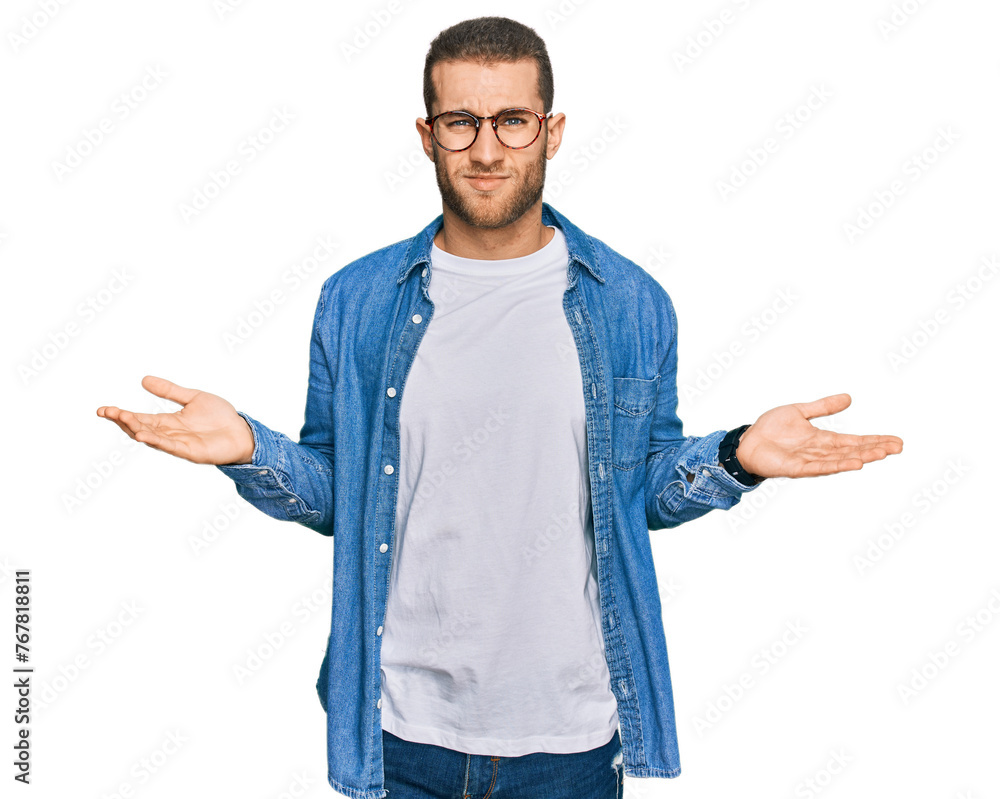 Wall mural Young caucasian man wearing casual clothes clueless and confused with open arms, no idea concept.