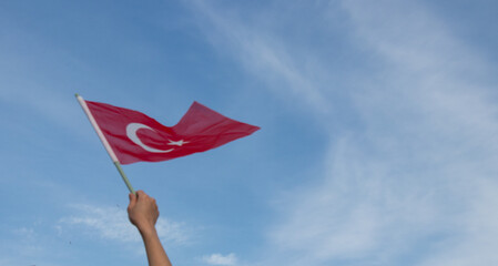 woman holding turkish flag, cop space area, against blue sky 