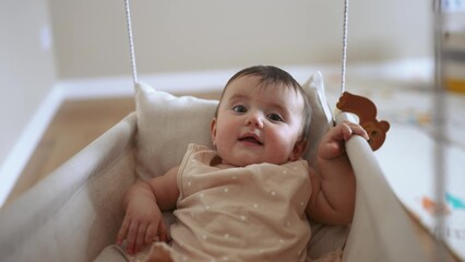 baby is swinging on a swing. baby blonde play at home sits on a rope swing. happy family kid dream kindergarten concept. pov view of baby playing in baby swing indoors lifestyle - 767821275