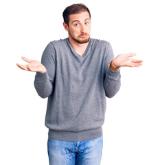 Young handsome caucasian man wearing casual winter sweater clueless and confused expression with...