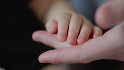 mother holds the hand of a newborn. children hand. hospital takes care of happy family medicine concept. newborn baby holding mom hand close-up. mom takes care close-up baby in the hospital - 767822803