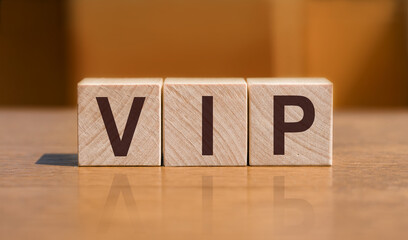 The word VIP consists of wooden cubes with letters, side view on a light background. Work space.