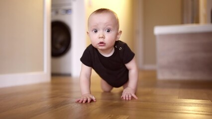 baby learns to crawl on the floor at home. happy family kindergarten kids concept. First steps, baby crawling front view . baby learns to crawl to explore the world around him dream - 767824093