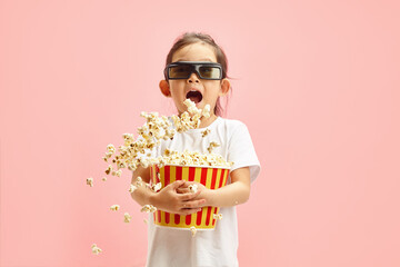 Joyful and Surprised Child Girl in 3D Glasses Holding Bucket of Popcorn Which is Flying to Sides...
