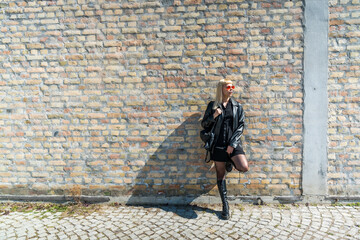 Fototapeta na wymiar Young beautiful strong independent rebel blonde woman Punk music and style fan posing. Confident Punk-Rock youth culture street style concept. Cool attitude bee different concept