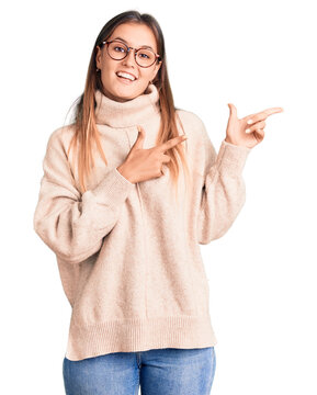 Beautiful caucasian woman wearing wool winter sweater smiling and looking at the camera pointing with two hands and fingers to the side.