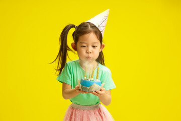  Focused Five Year Old Chinese Appearance Child in Party Hat Blow out Candles on Birthday Cake...