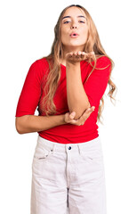 Young beautiful blonde woman wearing casual clothes looking at the camera blowing a kiss with hand on air being lovely and sexy. love expression.