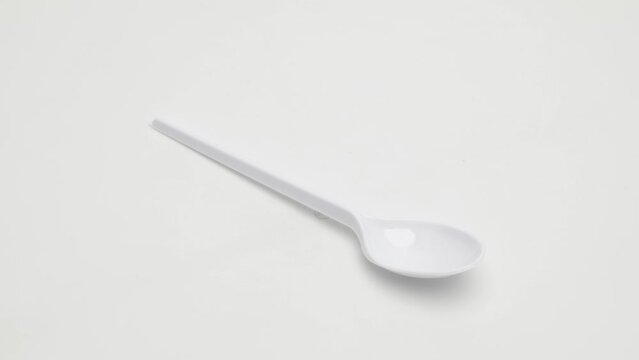 Plastic disposable spoon rotates on a white background.