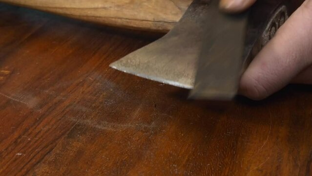 Tool closeup: Man sharpens old axe edge with whetstone on countertop