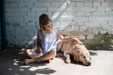 Friendship between a girl and a dog, a blonde girl stroking a Labrador, affection for pets, empathy...