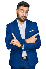 Young hispanic man wearing business jacket pointing to both sides with fingers, different direction...