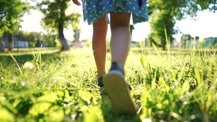 girl is playing in the forest park. close-up child legs walk on the park green grass in the park. happy family childhood dream concept. a child in sneakers walks on the grass in a park lifestyle - 767829643